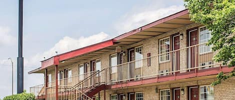 Un motel con fachada roja, varias ventanas y una escalera que lleva a la entrada.