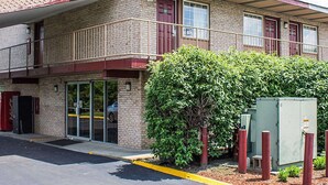 A two-story building with a brick facade, a red awning, and a small green bush in front. - Econo Lodge Columbus West (Columbus)