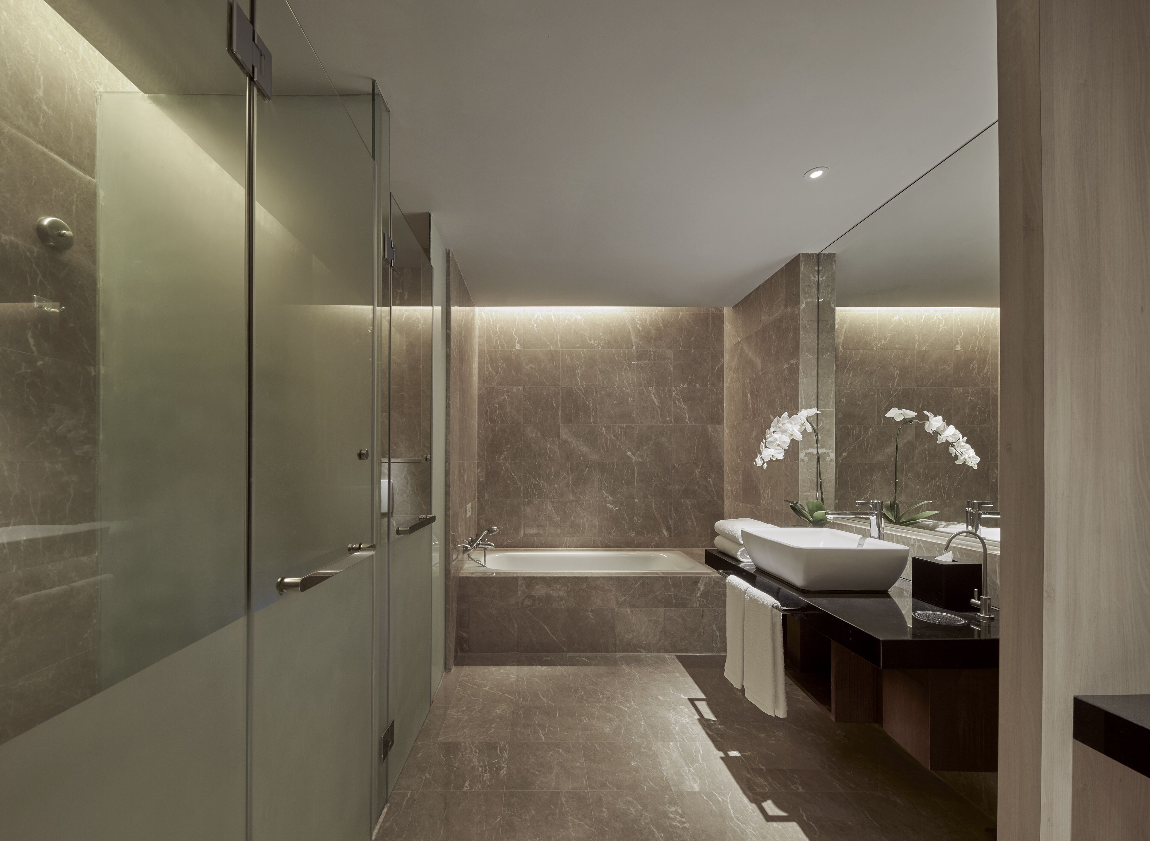 A modern bathroom with a glass shower enclosure, a freestanding bathtub, and a vanity with a sink and mirror.