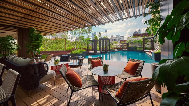 An outdoor patio with wooden slatted ceiling, wicker furniture, and a pool view. - PARKROYAL COLLECTION Kuala Lumpur (Kuala Lumpur)