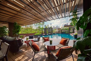 An outdoor patio with wooden slatted ceiling, wicker furniture, and a pool view. - PARKROYAL COLLECTION Kuala Lumpur (Kuala Lumpur)