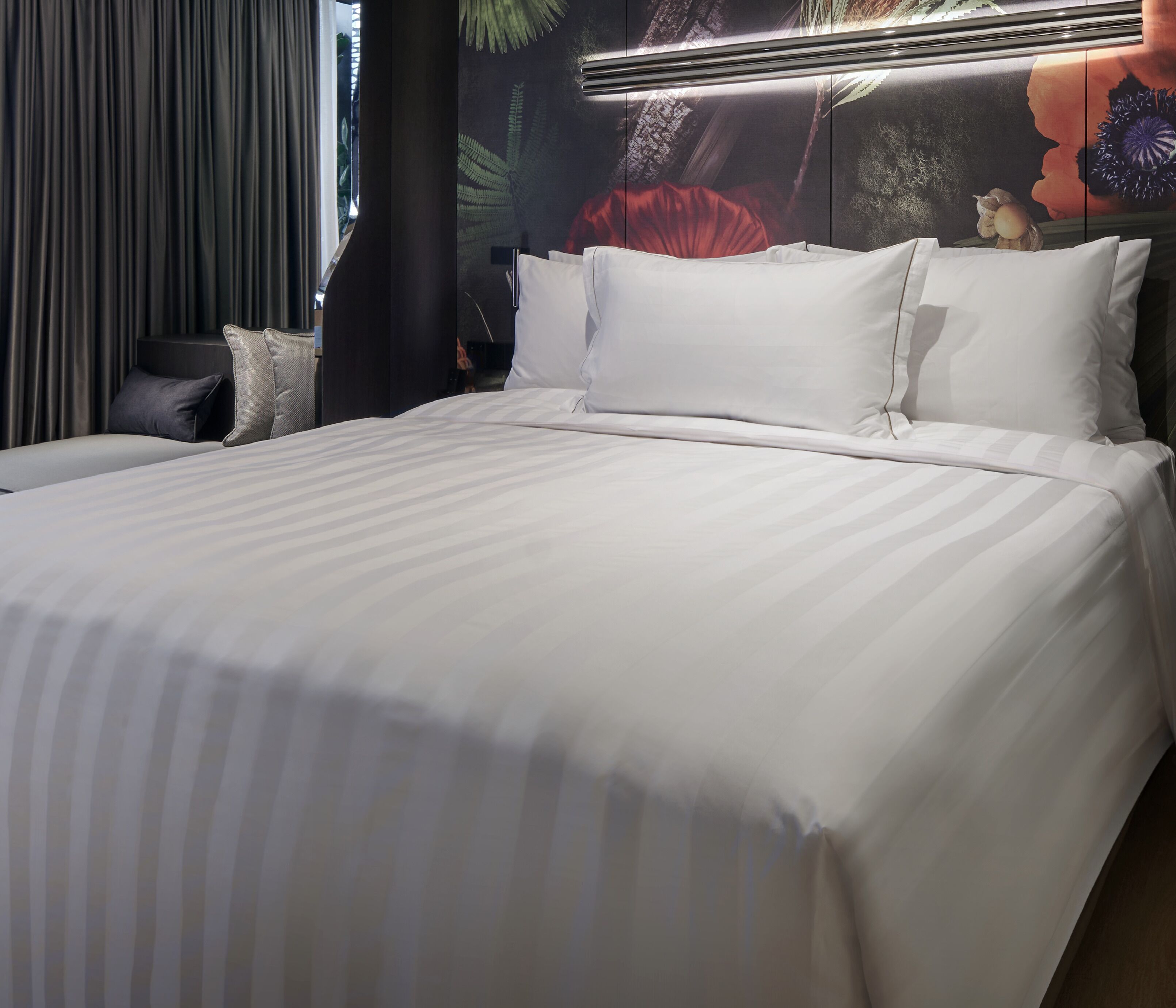 A neatly made bed with white linens in a hotel room.