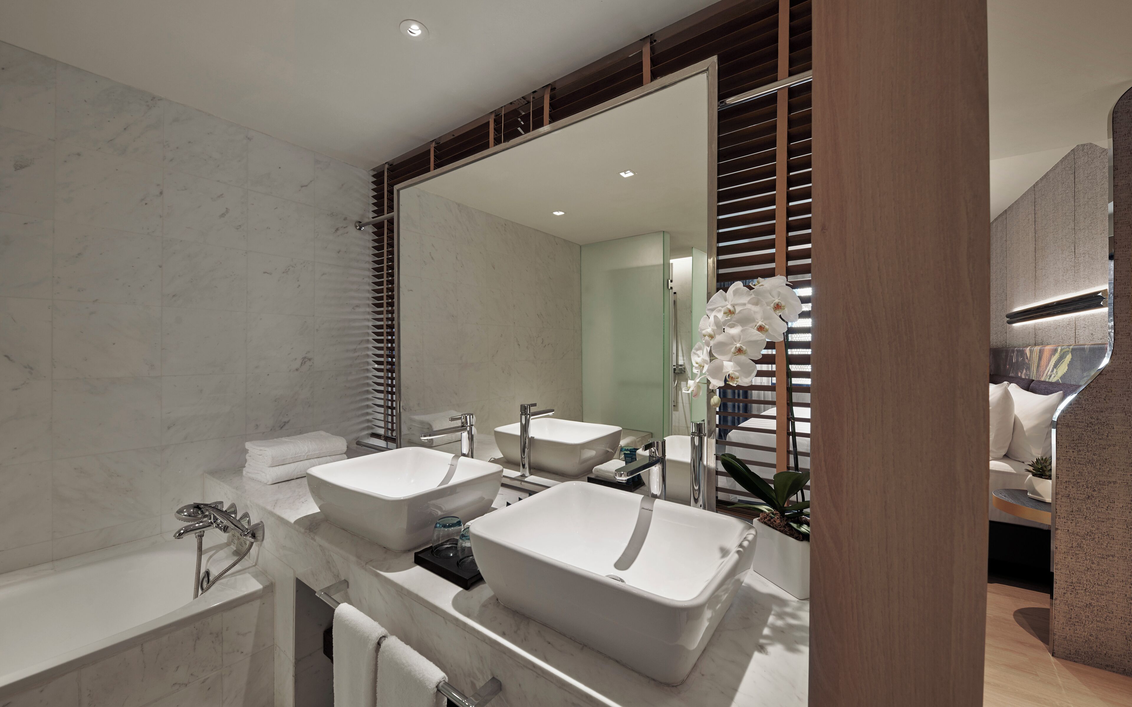 Une salle de bain moderne avec deux lavabos, une baignoire et un grand miroir.