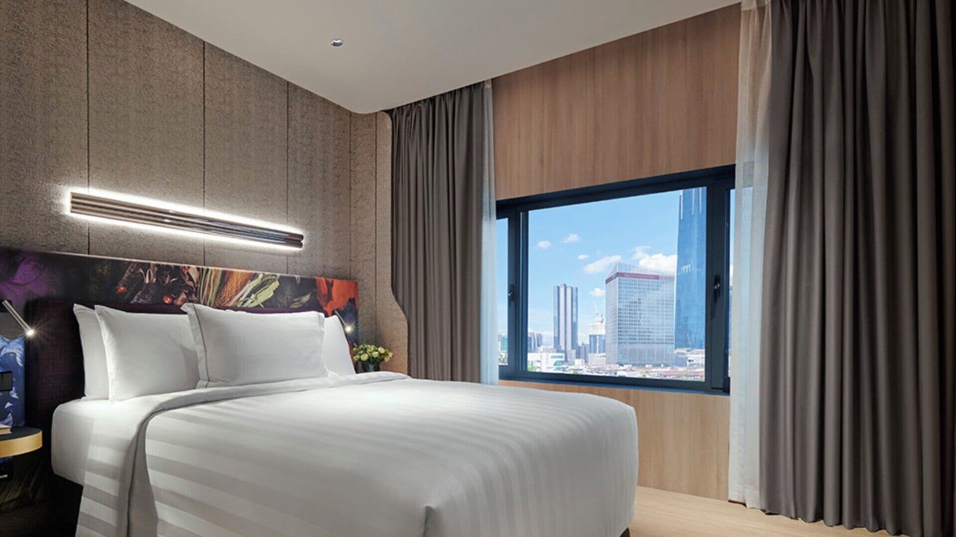 A modern hotel room with a large bed, a city view, and a contemporary design.
