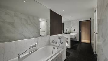 A modern bathroom with a bathtub, two sinks, and a large mirror.