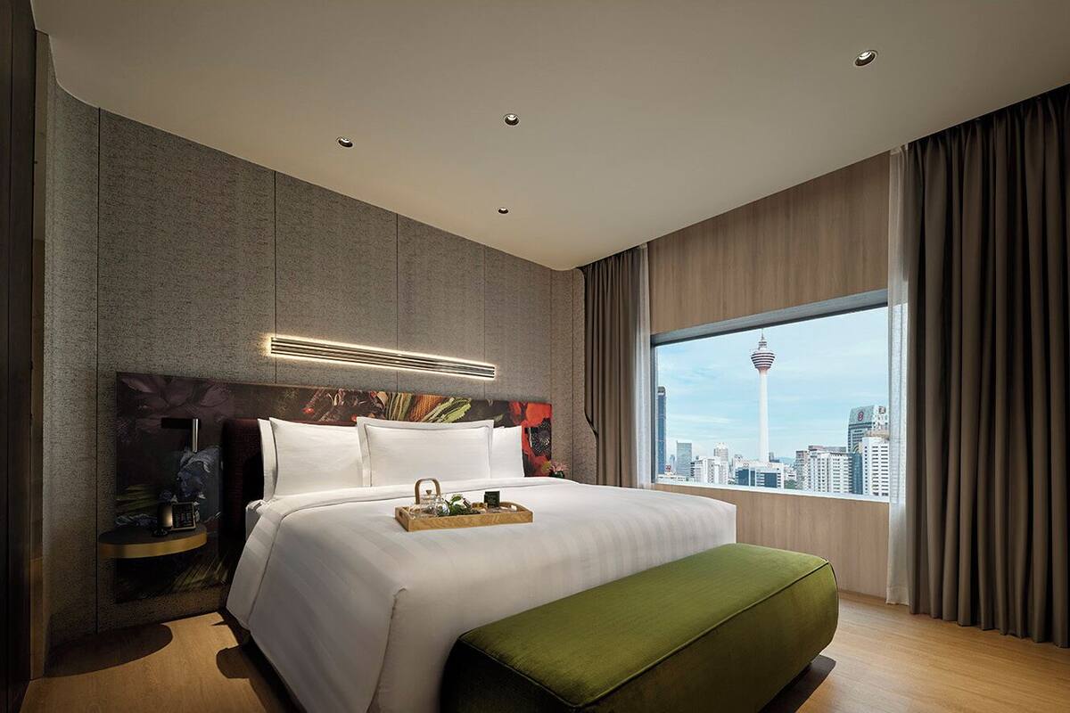 Une chambre d’hôtel moderne avec un grand lit, une vue sur la ville et un panorama urbain visible par la fenêtre.