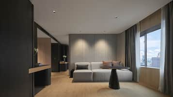 Una sala de estar moderna con un sofá modular, una mesita y vistas de la ciudad a través de grandes ventanales.