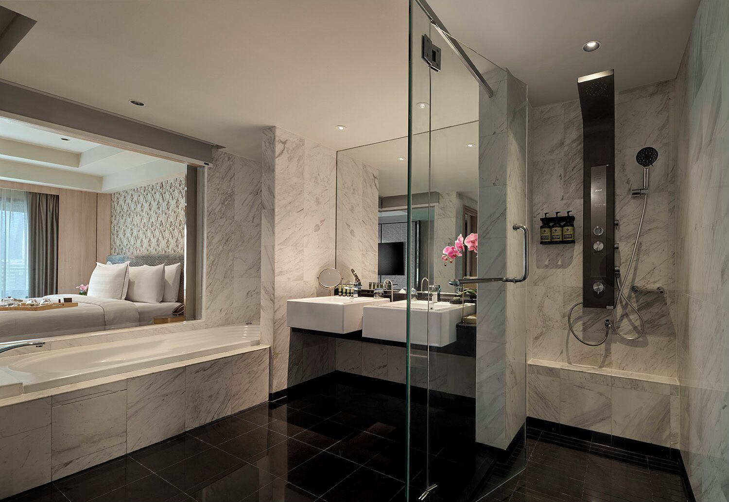 A modern bathroom with a glass-enclosed shower, a large bathtub, and a vanity with two sinks.