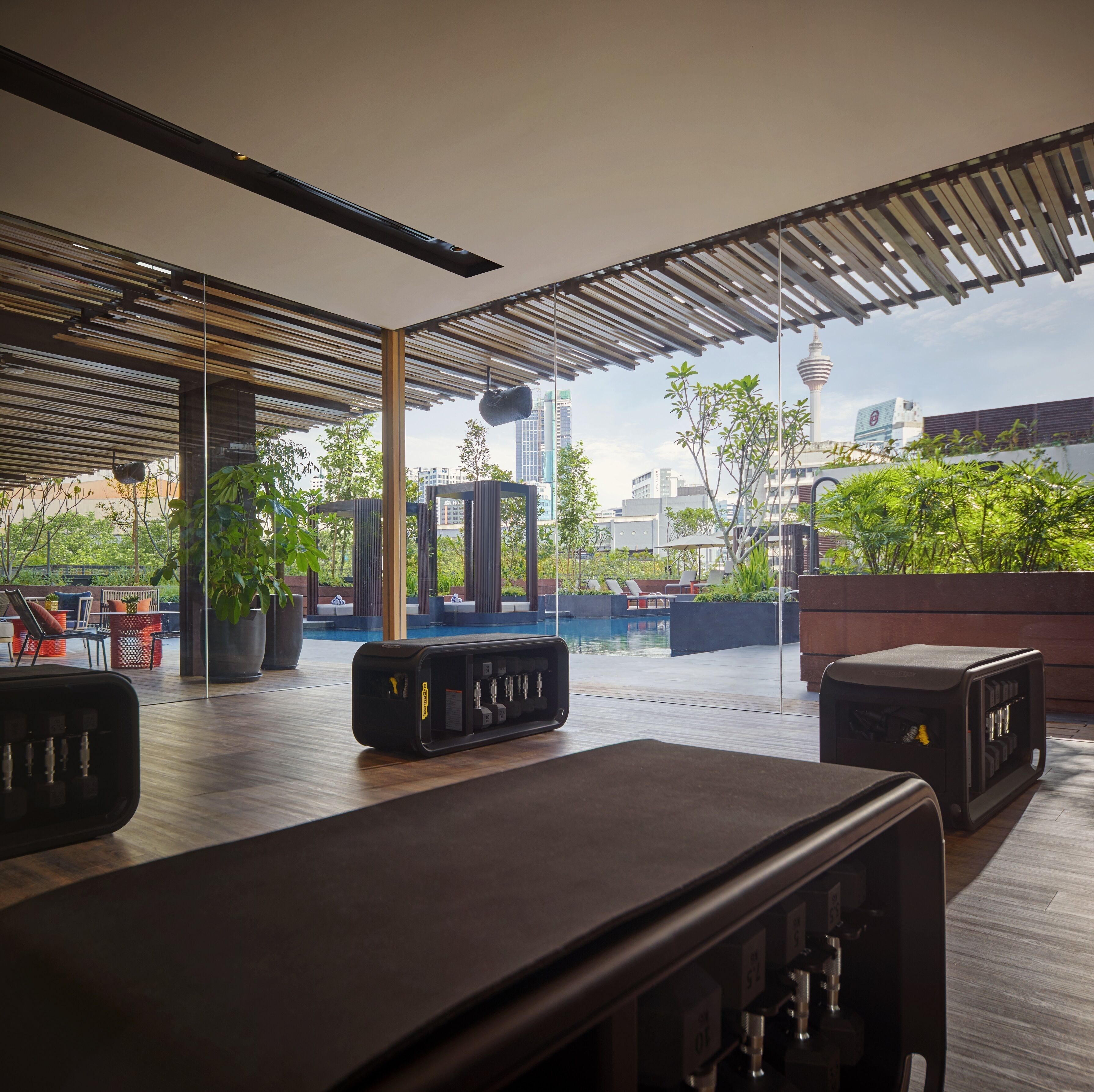 A modern outdoor lounge area with a pool, seating, and a view of the city skyline.