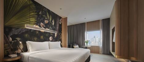 A modern hotel room with a large bed, a city view, and a decorative wall mural.