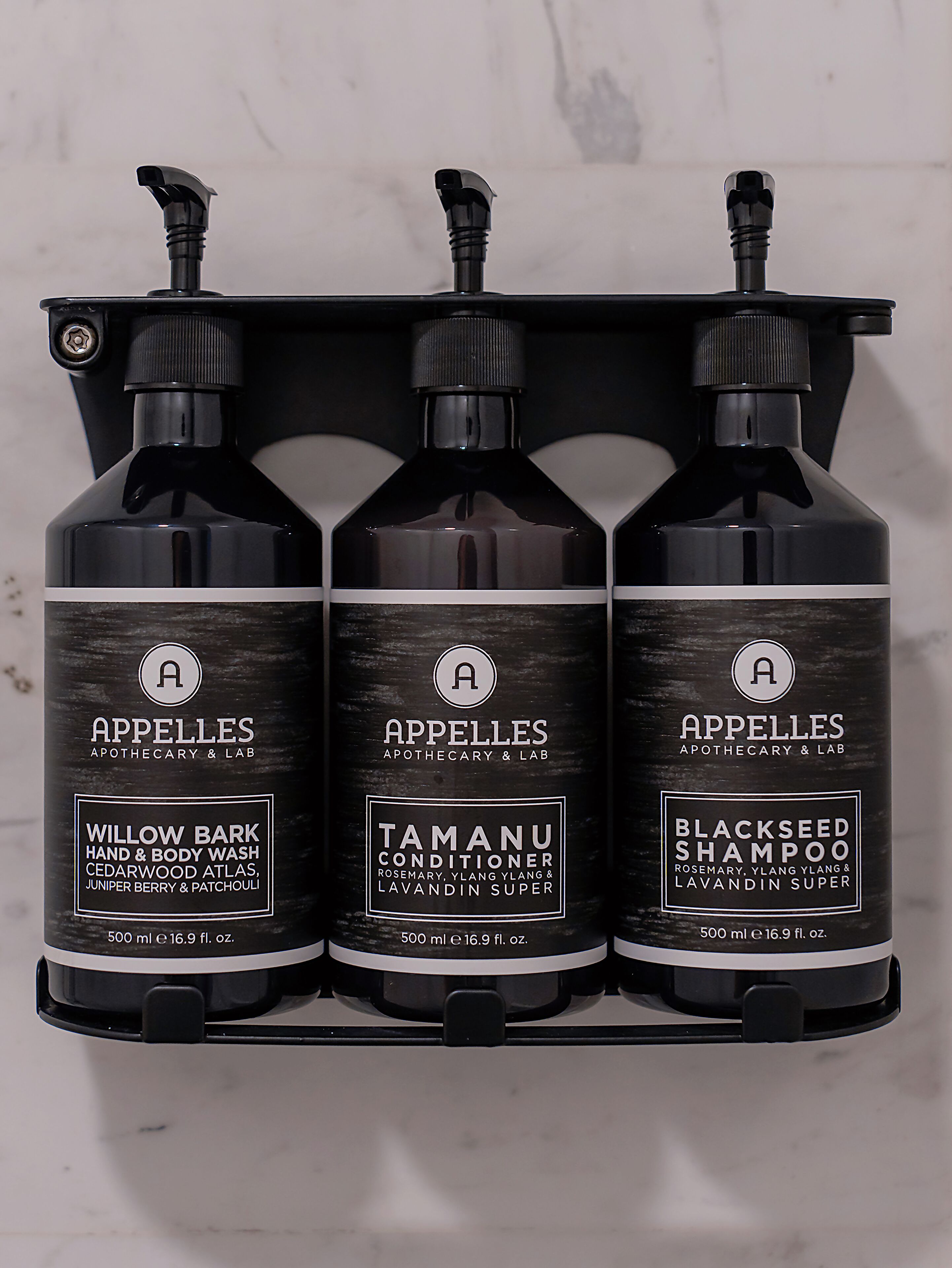 Three bottles of shampoo on a black shelf.