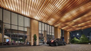 A modern building with a wooden slatted ceiling, large glass windows, and a paved entrance area. - PARKROYAL COLLECTION Kuala Lumpur (Kuala Lumpur)