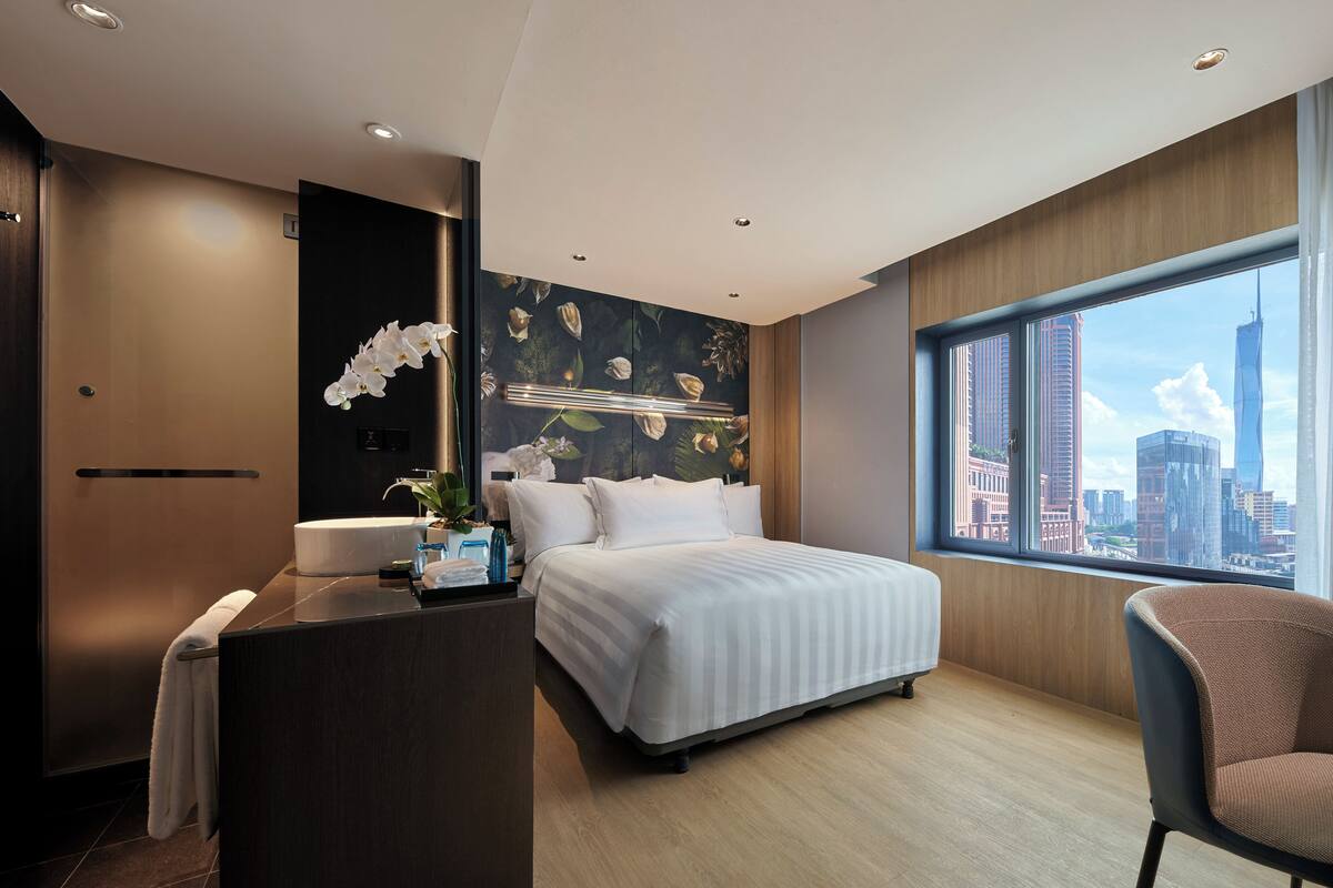 Une chambre d’hôtel moderne dotée d’un grand lit, d’un bureau, d’une salle de bain et offrant une vue sur la ville.