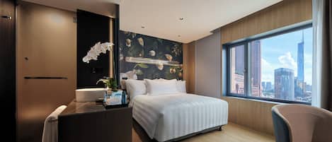 A modern hotel room with a large bed, a desk, a bathroom, and a city view.