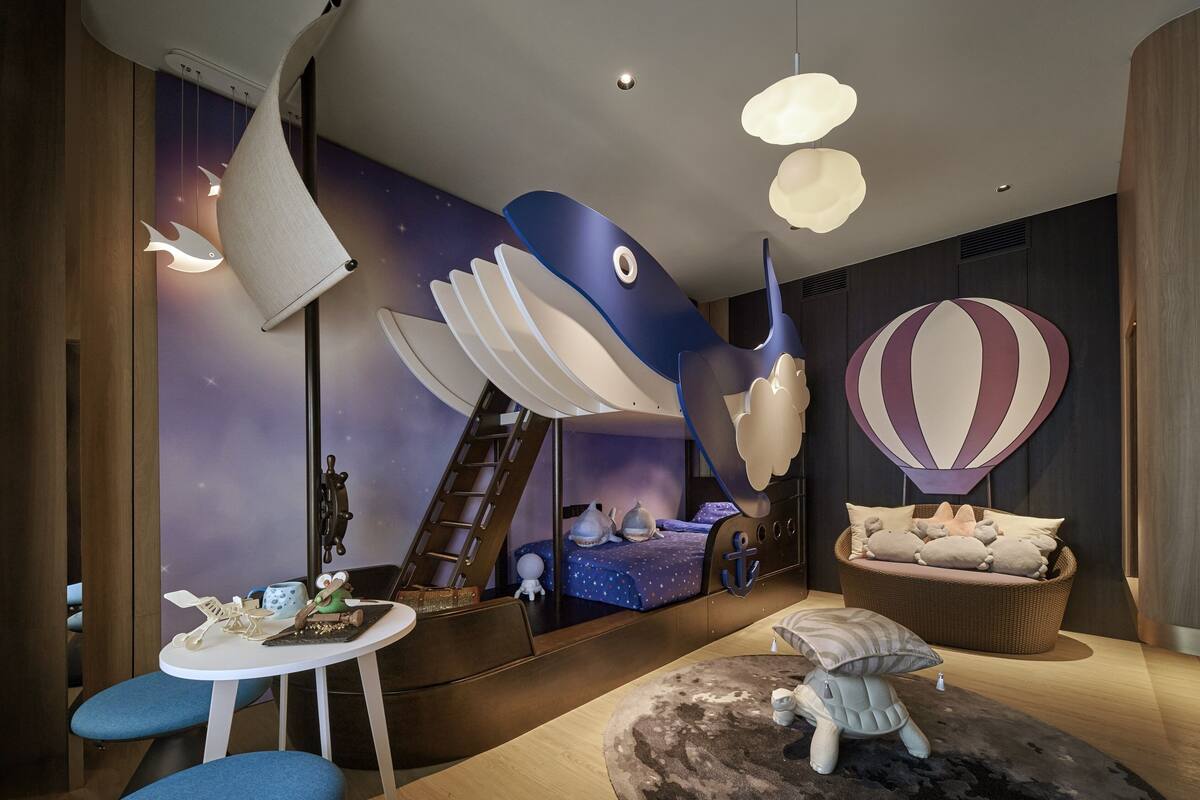 Une chambre d’enfant avec un lit superposé, une petite table et un espace de jeux.