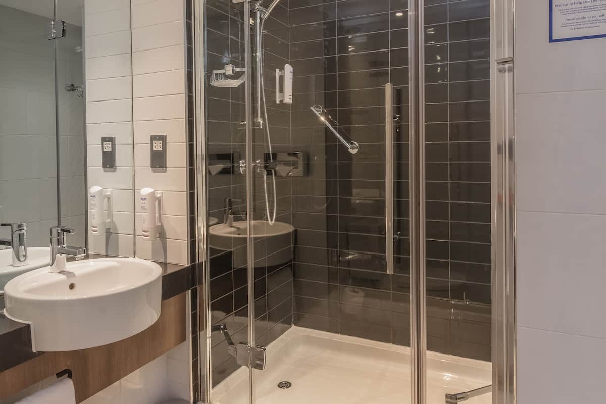 A modern bathroom with a glass-enclosed shower, a white sink, and a mirror.