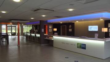 Ein Hotelrezeptionstresen mit digitaler Anzeige, einer Uhr und einem Schild für Holiday Inn Express.