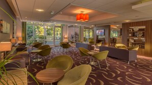A hotel lobby with seating areas, a reception desk, and a television. - Holiday Inn Express Preston - South by IHG (Preston)