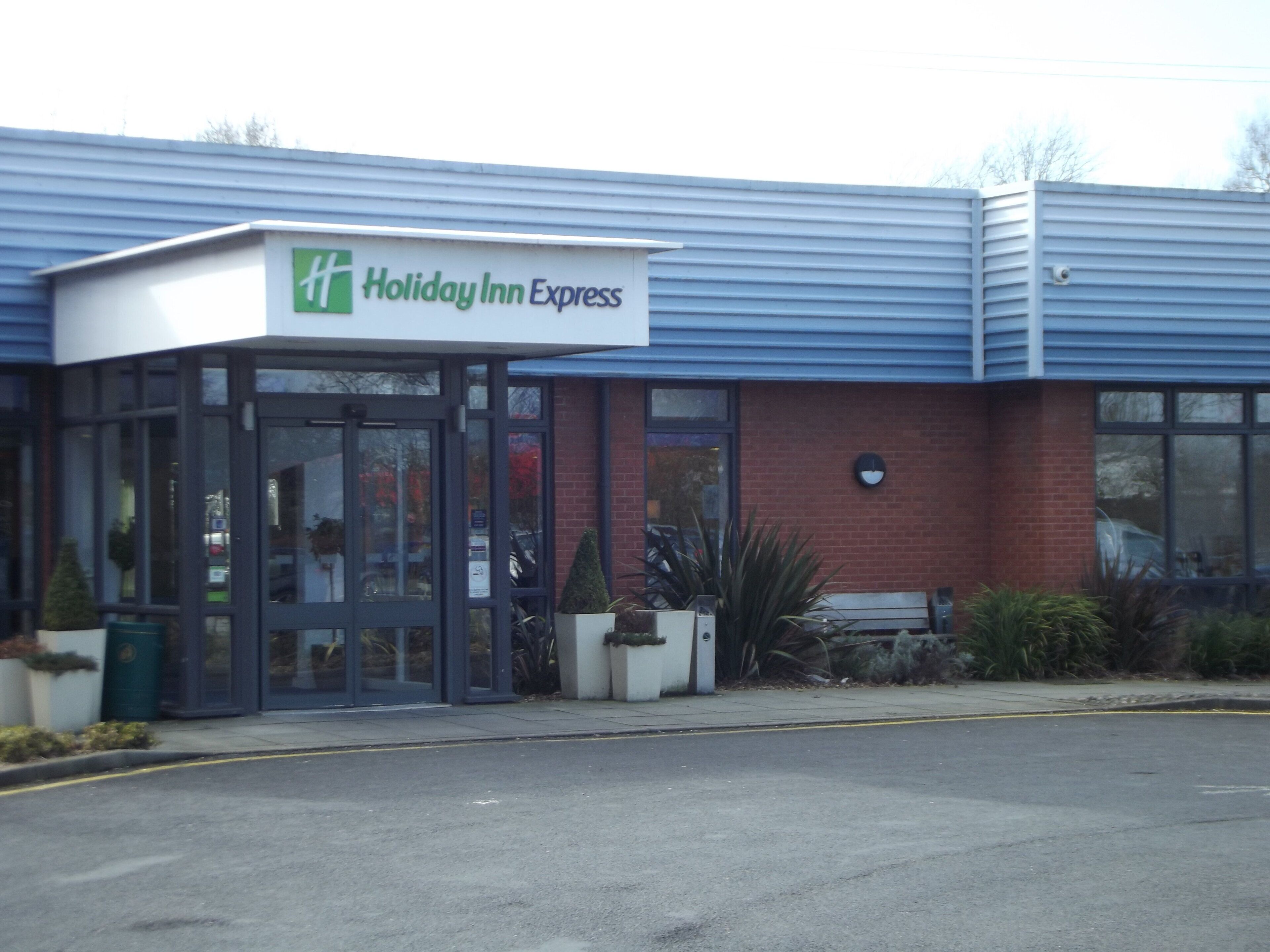 A Holiday Inn Express building with a glass entrance, a brick facade, and a blue roof.