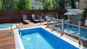 A swimming pool with a wooden deck, lounge chairs, and a glass fence. - Catalonia Mikado (Barcelona)