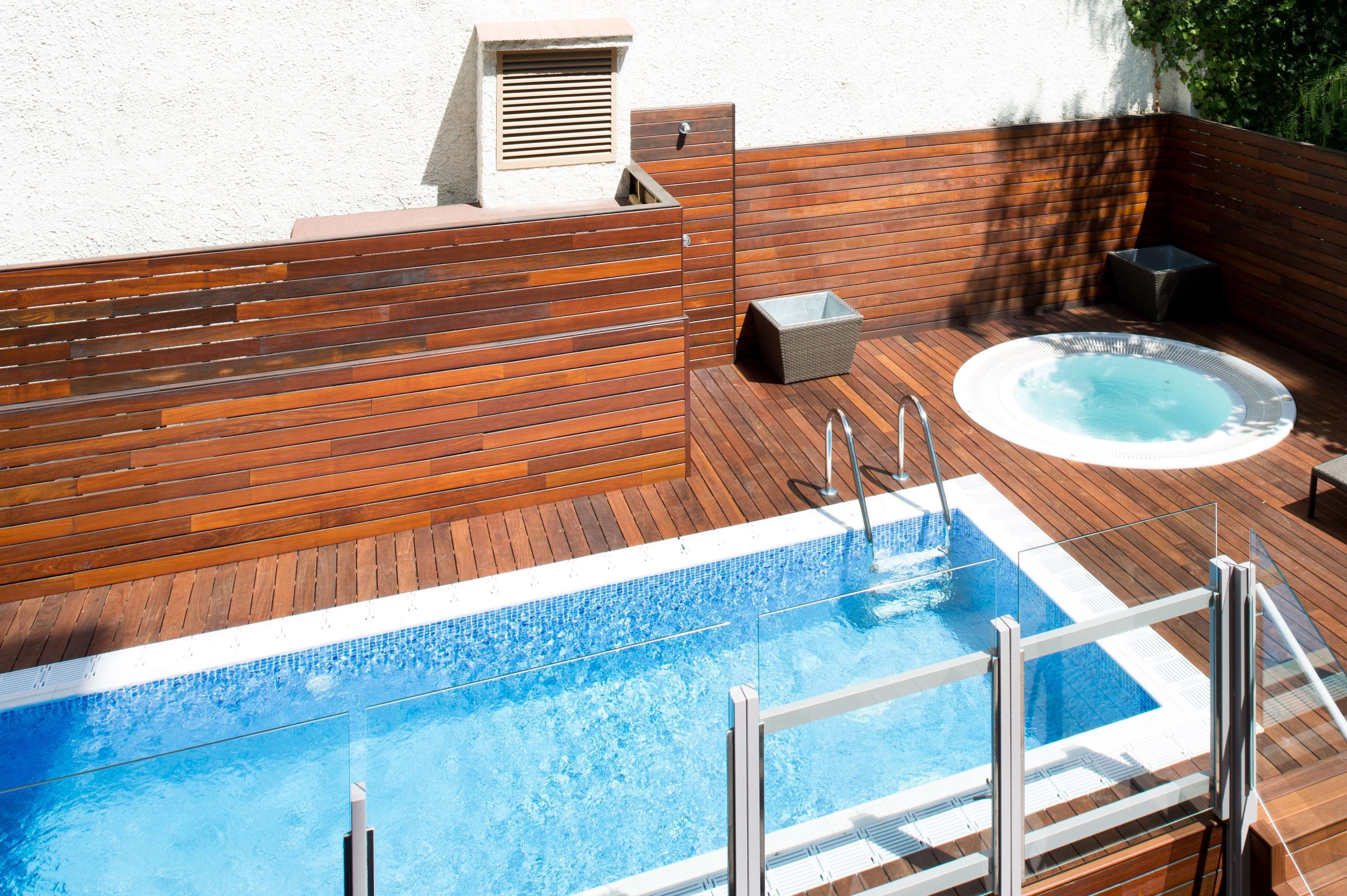 A swimming pool with a wooden deck and a hot tub.