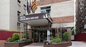 The entrance of Hotel Catalonia Mikado with a clear sign, a covered entrance, and a landscaped area with plants. - Catalonia Mikado (Barcelona)