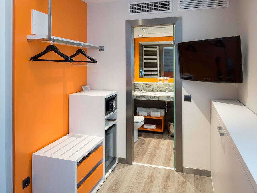 Casa de banho moderna com uma pia branca, espelho e porta-toalhas.