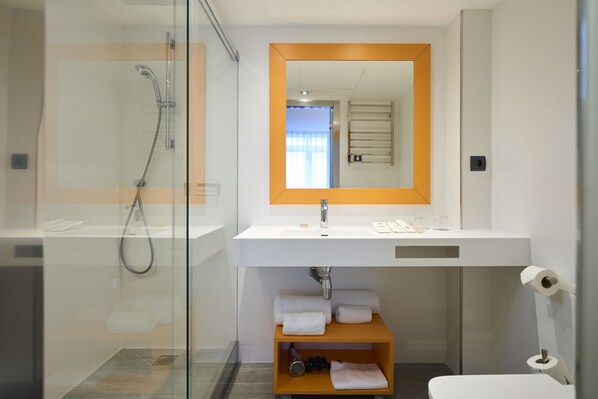 A modern bathroom with a glass-enclosed shower, a white sink with a mirror, and a towel shelf. - Catalonia Mikado (Barcelona)