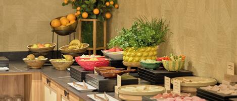 A buffet with various food items and a decorative plant.