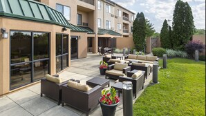 A hotel patio with outdoor seating, a covered area, and a well-maintained garden.