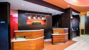 A reception area with two wooden reception desks, a red door, and a wall-mounted plant.