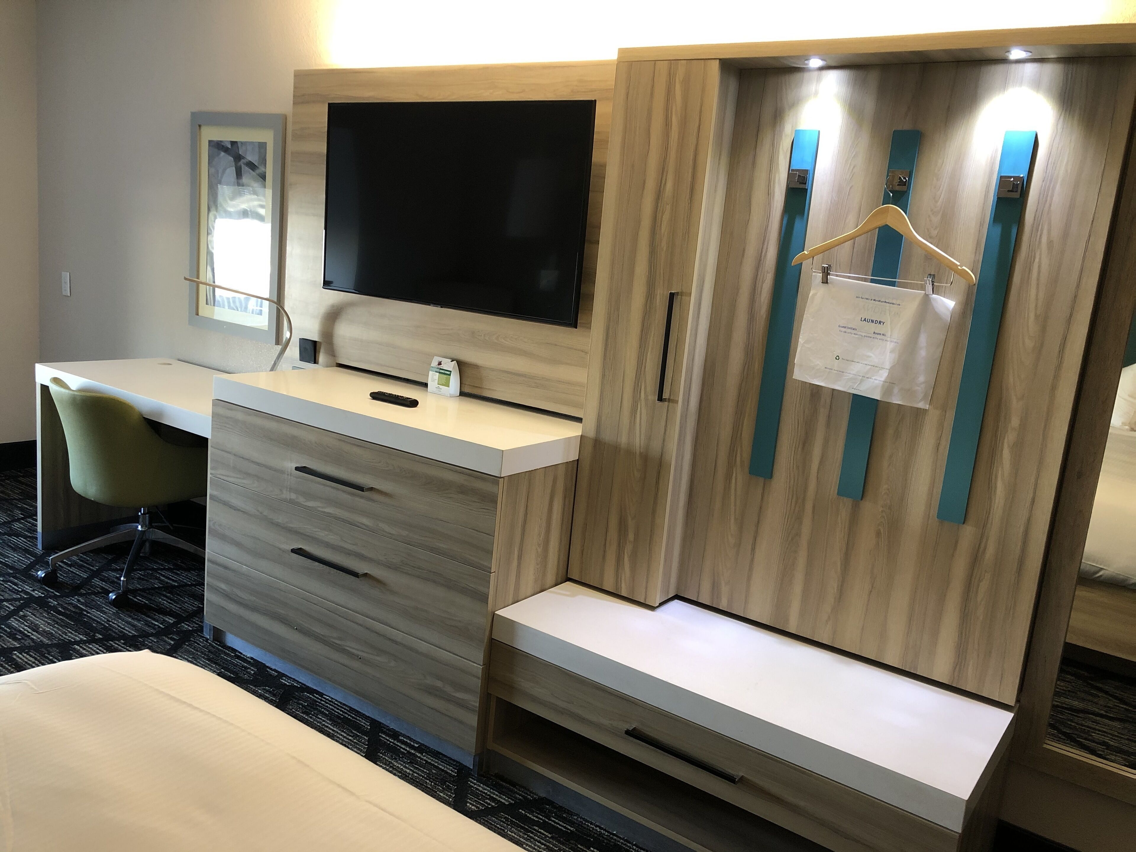 A hotel room with a desk, a chair, a TV, a wardrobe, and a bed.