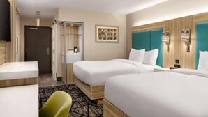Una habitación de hotel con dos camas, un escritorio, una silla, un televisor y un baño.