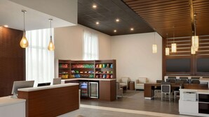 Una zona de recepción moderna con un mostrador de madera, un bar de aperitivos y áreas de estar.