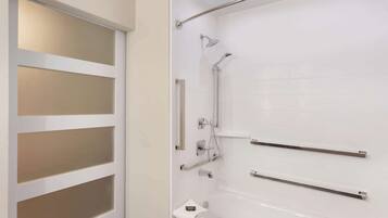 A modern bathroom with a glass door, a bathtub, and a shower area.