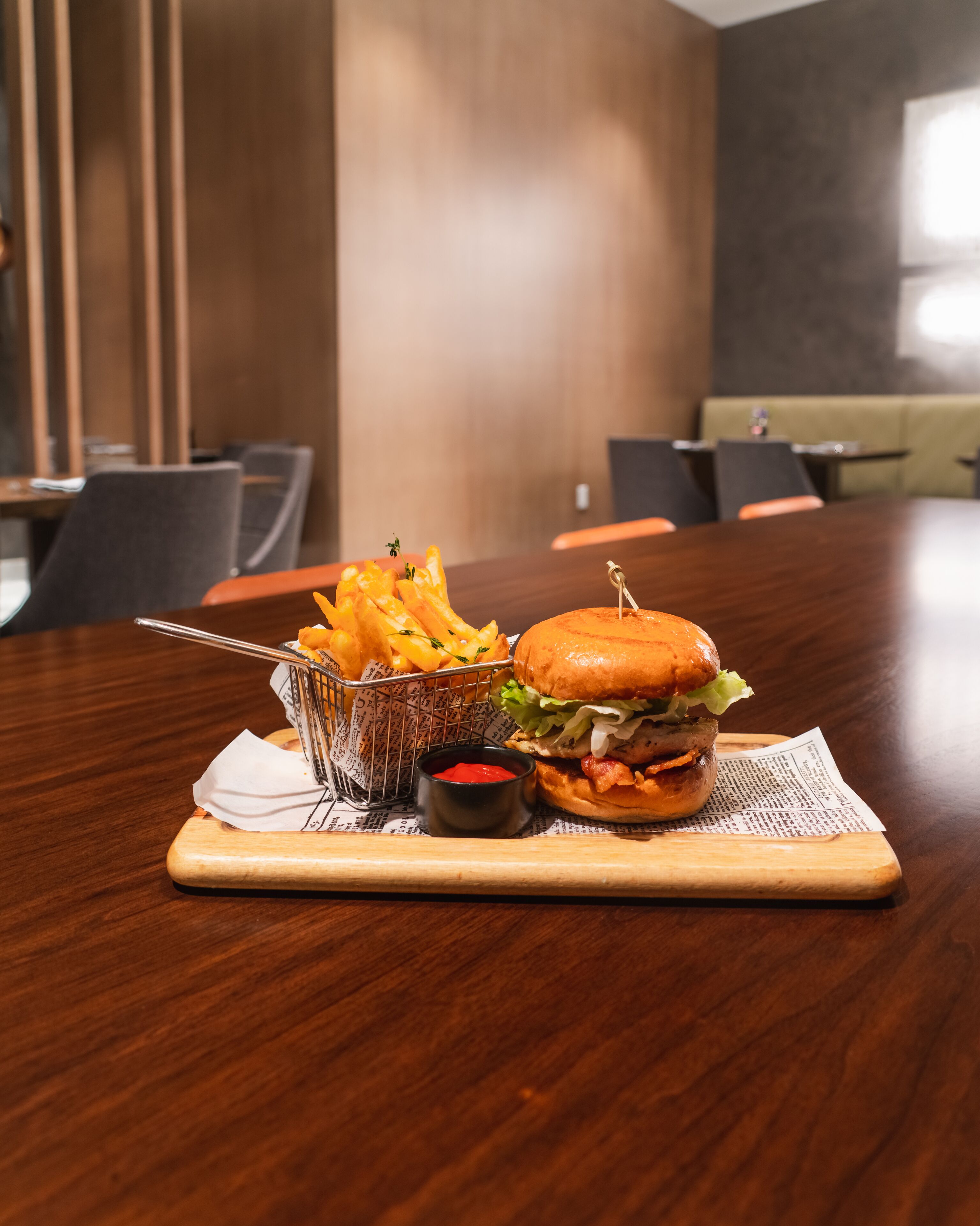 A dining table with a burger, fries, and ketchup.