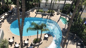 A resort pool area with multiple swimming pools, lounge chairs, and tables. - Hyatt Regency Newport Beach West (Newport Beach)