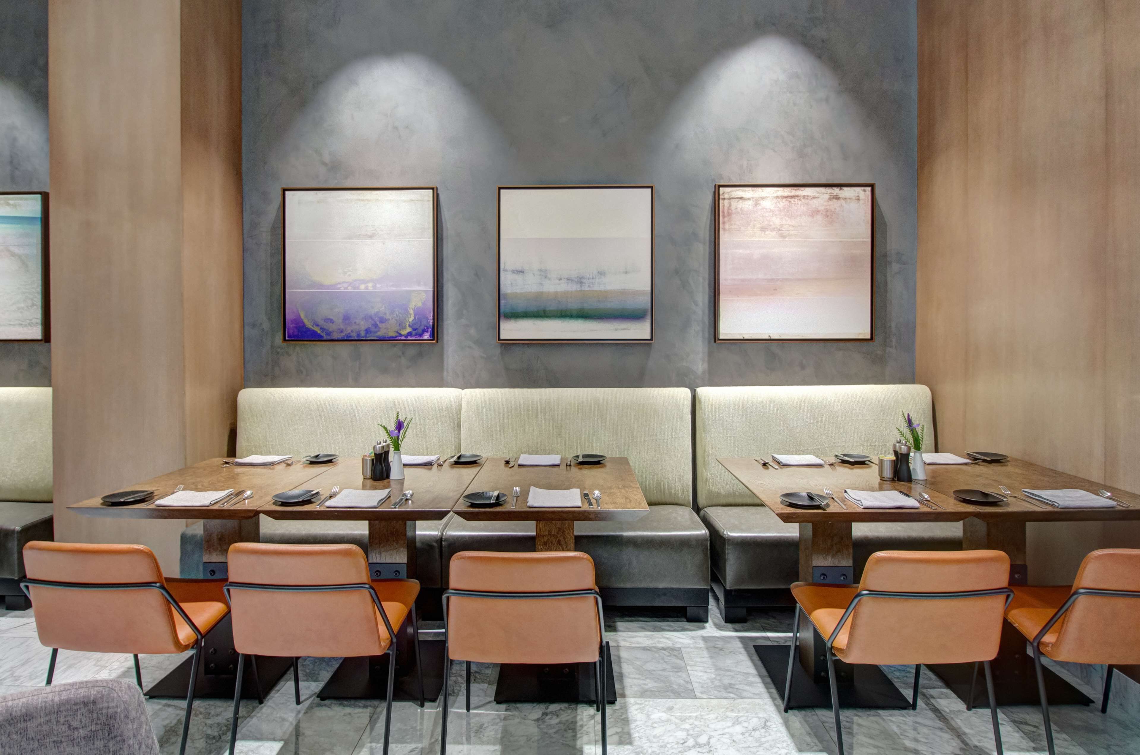 A modern dining area with booths and tables, framed artwork on the walls, and a neutral color palette.