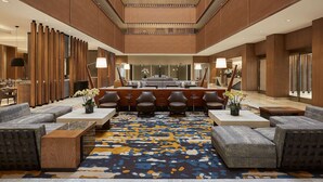 A spacious lobby with a central seating area, a patterned carpet, and wooden paneling on the walls. - Hyatt Regency Newport Beach West (Newport Beach)