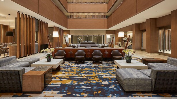 A spacious lobby with a central seating area, a patterned carpet, and wooden paneling on the walls. - Hyatt Regency Newport Beach West (Newport Beach)
