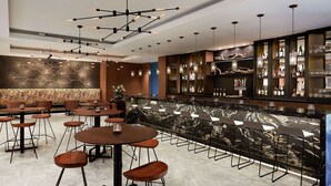 A modern bar area with a marble countertop, bar stools, and a variety of bottles and glasses. - Hyatt Regency Newport Beach West (Newport Beach)