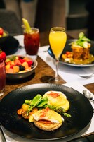Un desayuno con una variedad de platos, incluyendo huevos, tostadas y verduras, junto con dos bebidas.