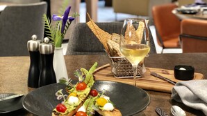 A dining table with a plate of food, a glass of wine, and a bread basket. - Hyatt Regency Newport Beach West (Newport Beach)