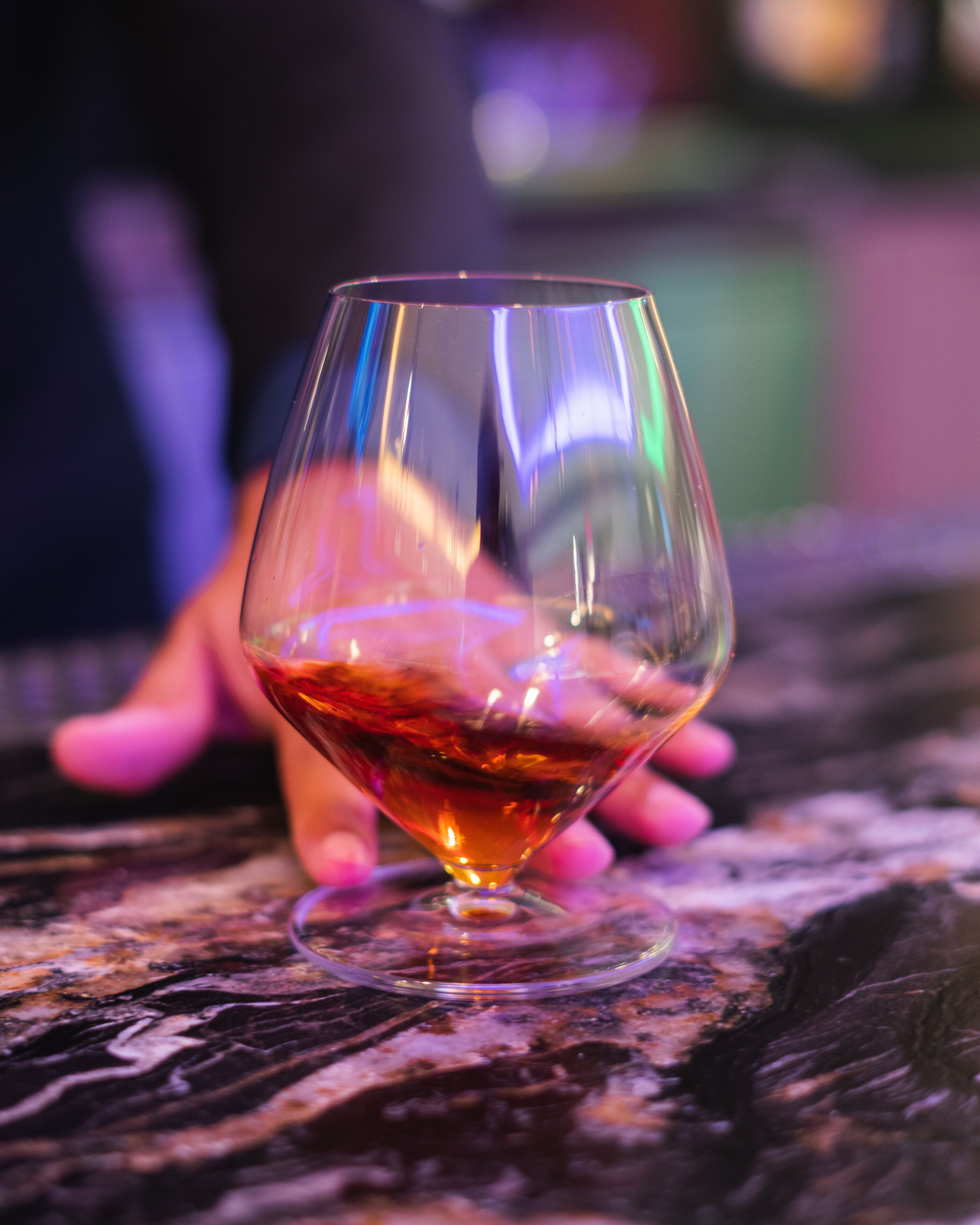 A glass of amber liquid on a textured surface.