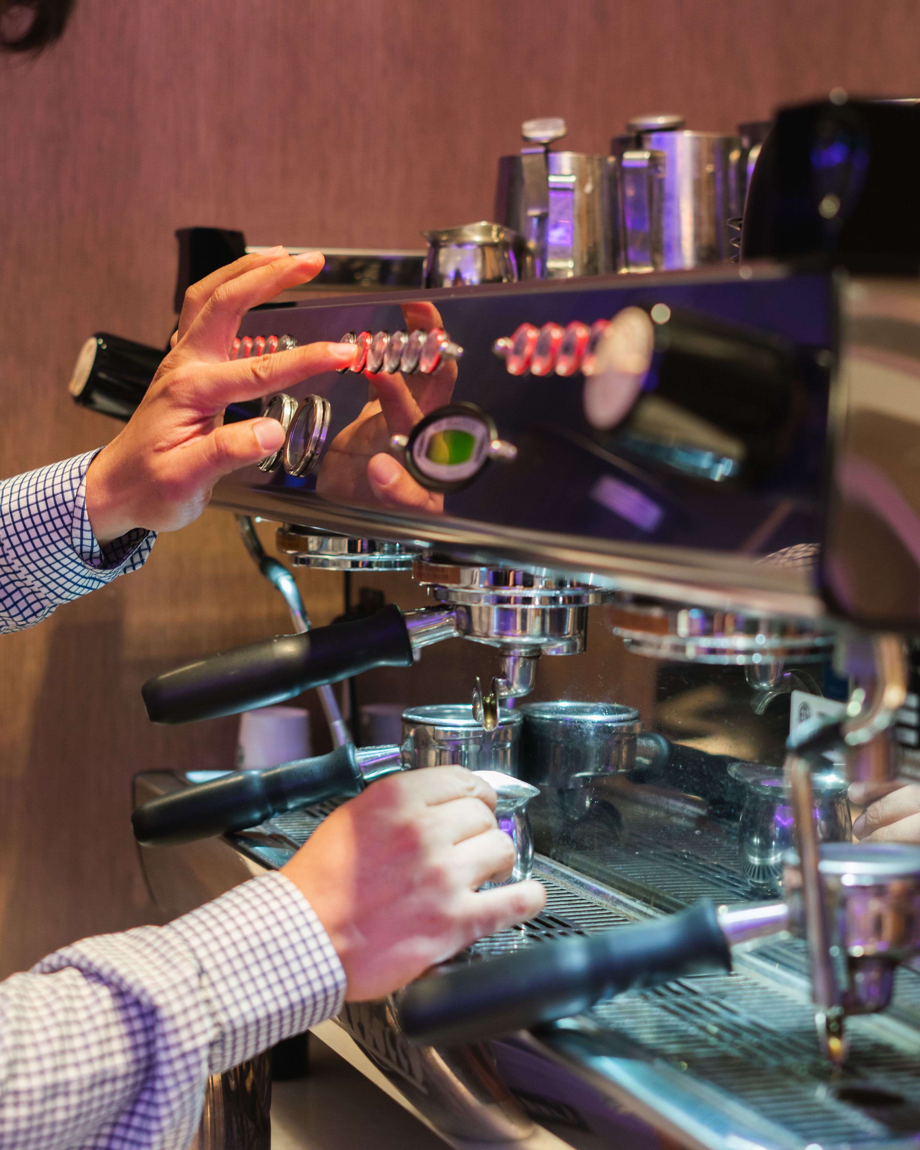 Una persona operando una máquina de café espresso, con énfasis en la interfaz y los distintos componentes de la máquina.