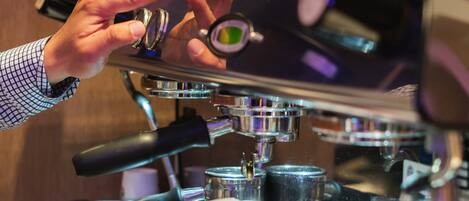 Una persona operando una máquina de café espresso, con énfasis en la interfaz y los distintos componentes de la máquina.