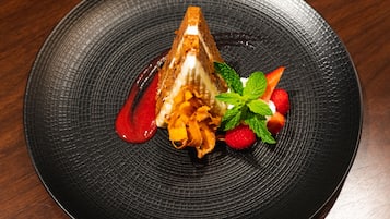 Un dessert présenté sur une assiette noire à texture, avec une table en bois en arrière-plan.
