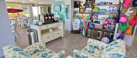 A cozy interior with floral-patterned sofas, a coffee station, and a variety of items on shelves.