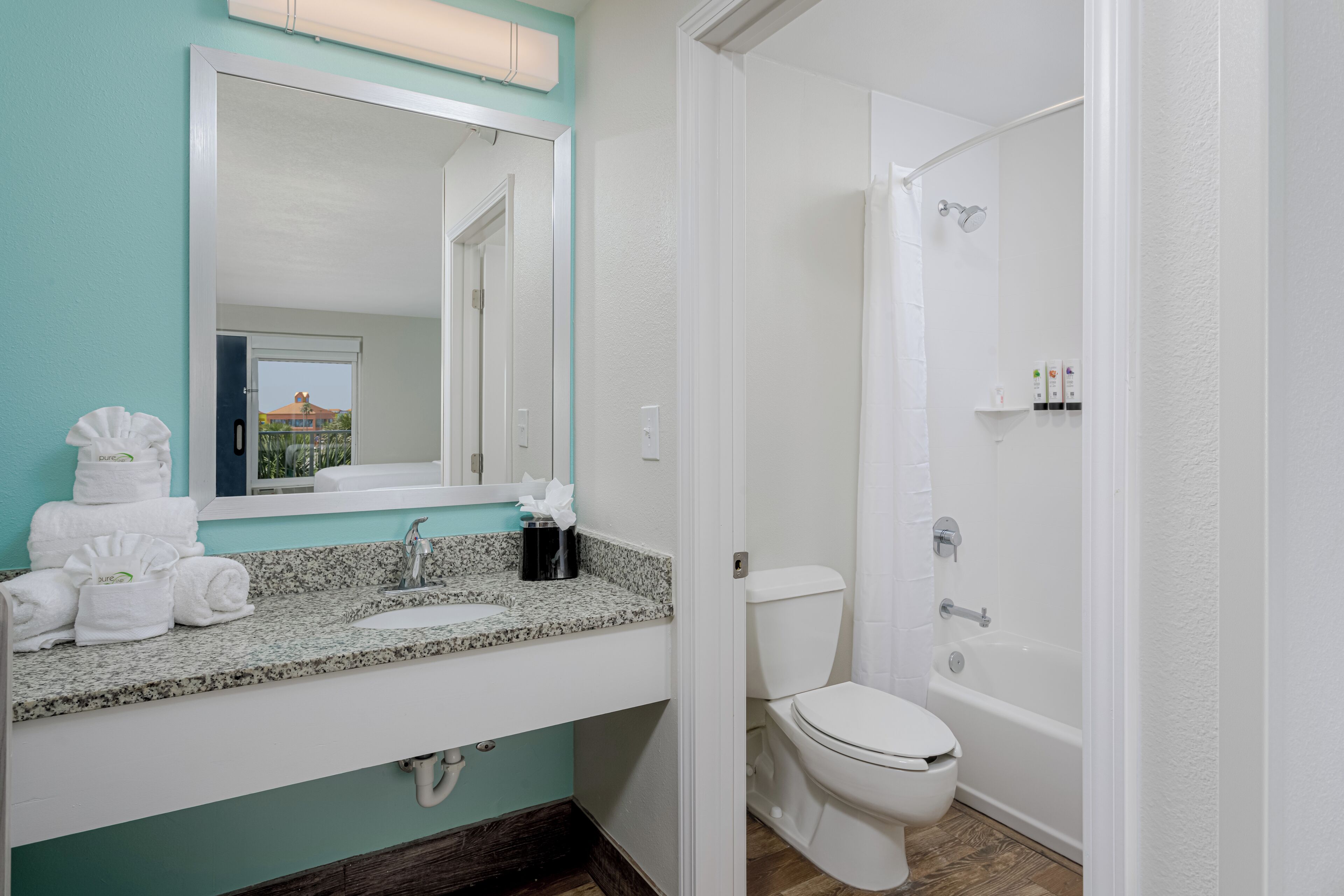 Een badkamer met een wastafel, spiegel, toilet en bad.