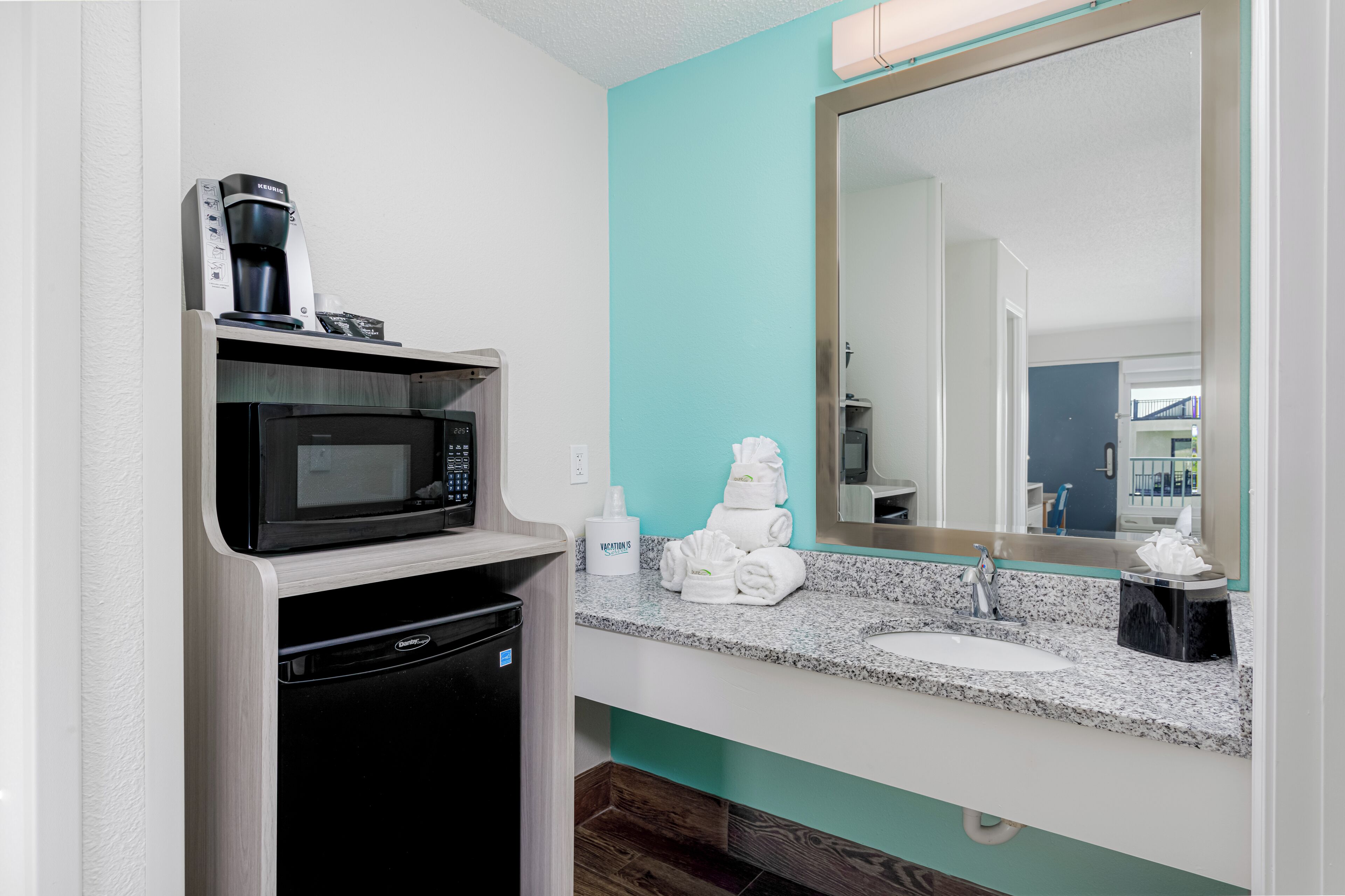 Une salle de bain moderne équipée d’un four à micro-ondes encastré, d’une machine à café et d’un lavabo avec un plan de travail en granit.